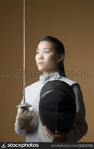 Close-up of a female fencer holding a sword and a fencing mask
