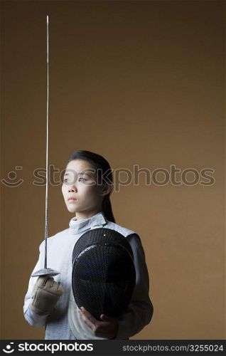 Close-up of a female fencer holding a sword and a fencing mask