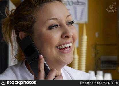 Close-up of a female ice-cream shop owner talking on a mobile phone