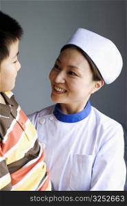 Close-up of a female nurse and a boy smiling and looking at each other