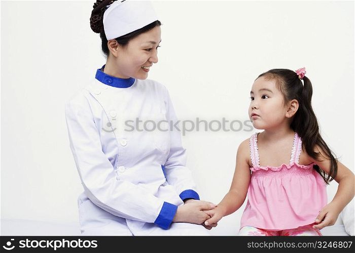 Close-up of a female nurse and a girl child holding hands