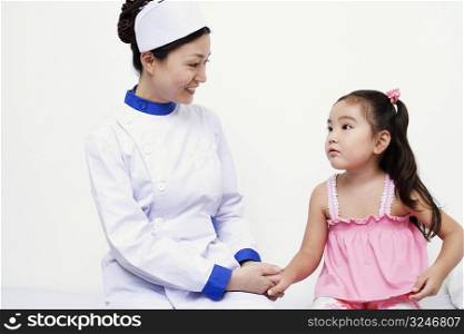 Close-up of a female nurse and a girl child holding hands