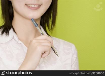 Close-up of a female office worker holding a pen and smiling