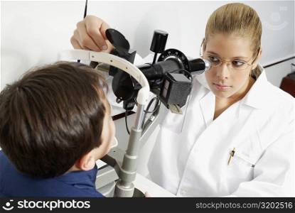 Close-up of a female optometrist examining eyes of a boy