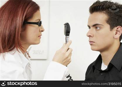 Close-up of a female optometrist examining eyes of a young man