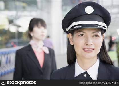 Close-up of a female pilot smiling with a female cabin crew behind her