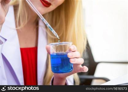 Close-up of a female researcher carrying out research in a chemistry lab scientist holding test tube with sample in Laboratory analysis background