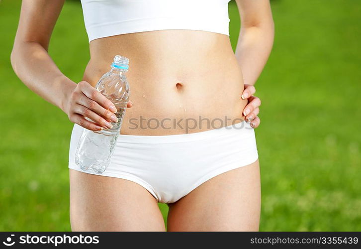 Close up of a female stomach and hand with water