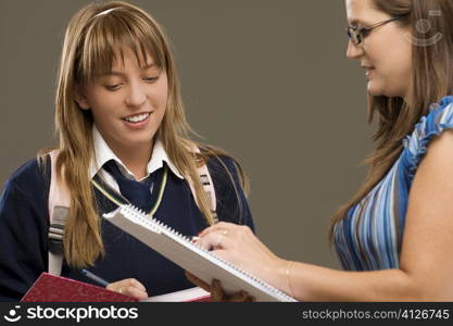 Close-up of a female teacher checking notebook of a teenage girl