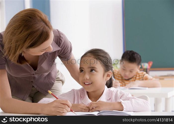 Close-up of a female teacher teaching a schoolgirl in a classroom
