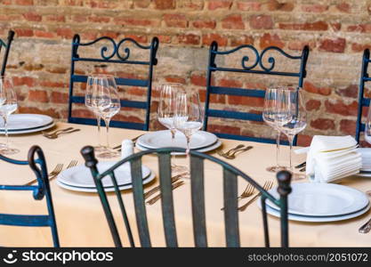 Close up of a festive table setting with empty wine glasses and white plates. Table setting for special events.