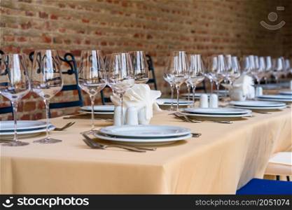Close up of a festive table setting with empty wine glasses and white plates. Table setting for special events.