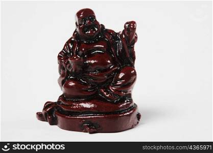 Close-up of a figurine of Laughing Buddha against white background