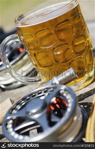 Close-up of a fishing reel and a fishing rod with a glass of beer