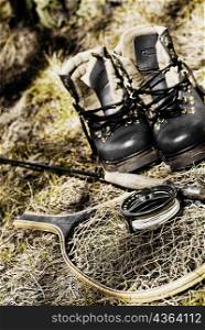 Close-up of a fishing rod with a fishing net and a pair of shoes