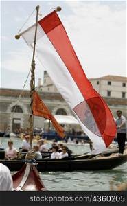 Close-up of a flag on a gondola with a group of people behind in another gondola, Venice, Veneto, Italy