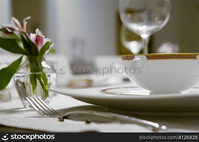 Close-up of a flower vase and a soup bowl on a dining table