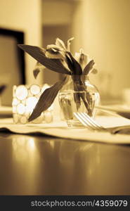 Close-up of a flower vase with a candlestick holder on a dining table