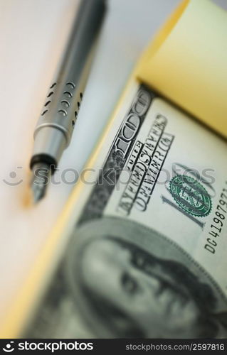 Close-up of a fountain pen and one hundred dollar bill