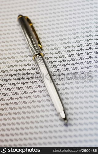 Close-up of a fountain pen on a sheet of percentage signs