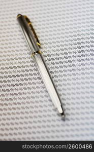 Close-up of a fountain pen on a sheet of percentage signs