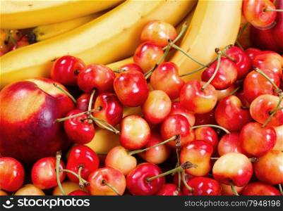 Close up of a fresh pile of fruit consisting of cherries, peaches and bananas. Layout in filled frame format.