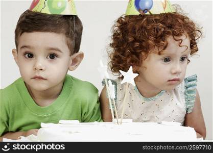 Close-up of a girl and a boy wearing birthday hats