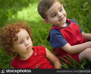 Close-up of a girl and her brother sitting on the grass