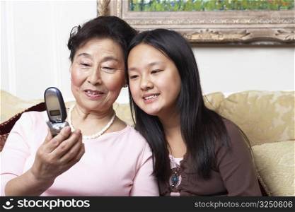 Close-up of a girl and her grandmother looking at a mobile phone