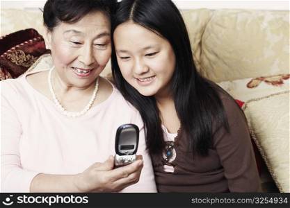 Close-up of a girl and her grandmother looking at a mobile phone