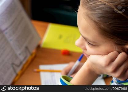 Close-up of a girl doing homework, a girl lost in thought distracted from the task