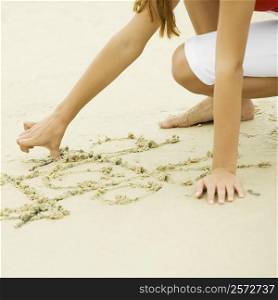 Close-up of a girl drawing in sand on the beach
