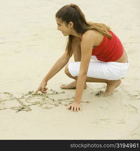 Close-up of a girl drawing in sand on the beach