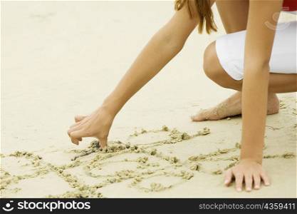 Close-up of a girl drawing in sand on the beach