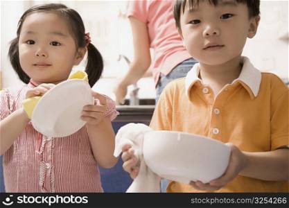Close-up of a girl drying plates with her brother