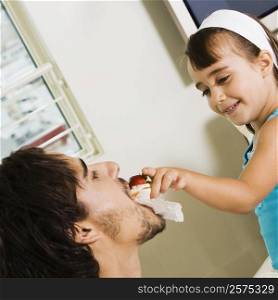 Close-up of a girl feeding her father
