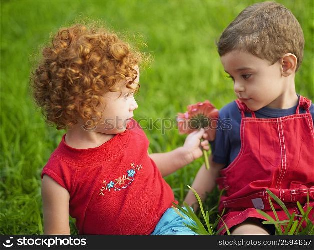 Close-up of a girl giving a flower to her brother