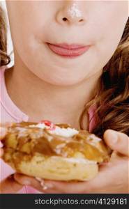 Close-up of a girl holding a bagel with cream on her nose
