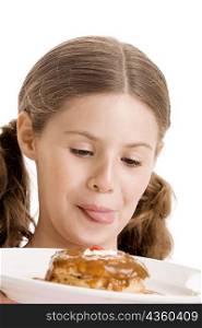 Close-up of a girl holding a donut in a plate licking her lips