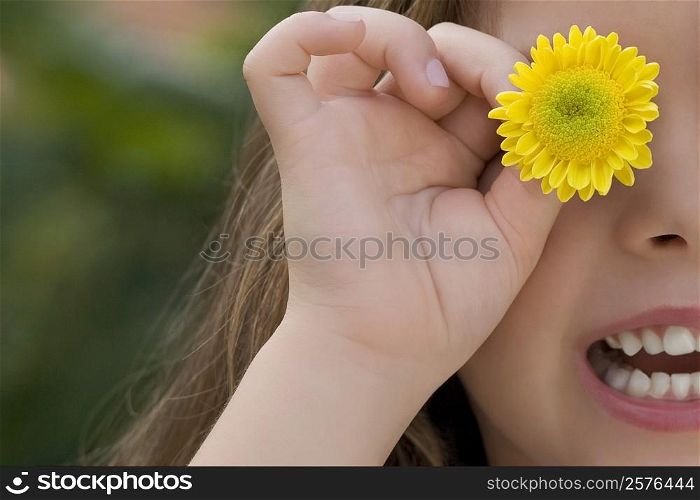Close-up of a girl holding a flower on her eye