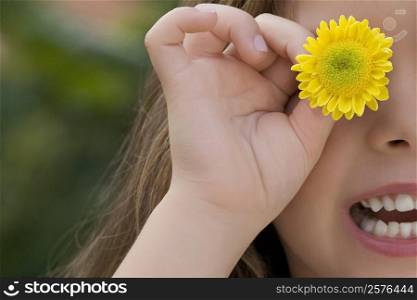 Close-up of a girl holding a flower on her eye
