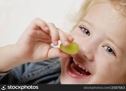 Close-up of a girl holding a grape and smiling