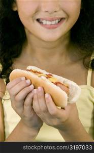 Close-up of a girl holding a hot dog and smiling