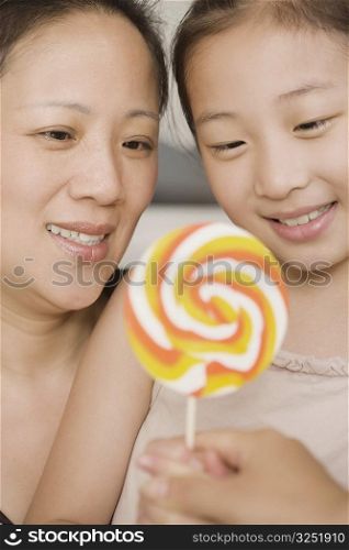 Close-up of a girl holding a lollipop with her mother