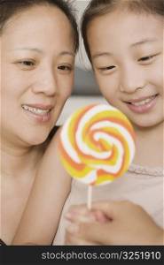 Close-up of a girl holding a lollipop with her mother
