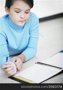 Close-up of a girl holding a pen and looking at a spiral notebook