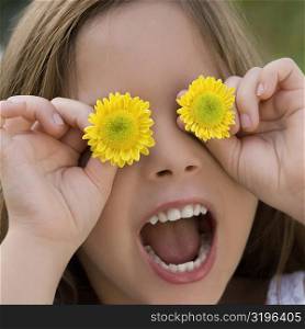 Close-up of a girl holding flowers over her eyes