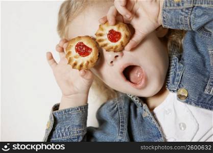 Close-up of a girl holding two biscuits on her eyes