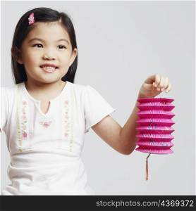 Close-up of a girl holding two Chinese lanterns and smiling