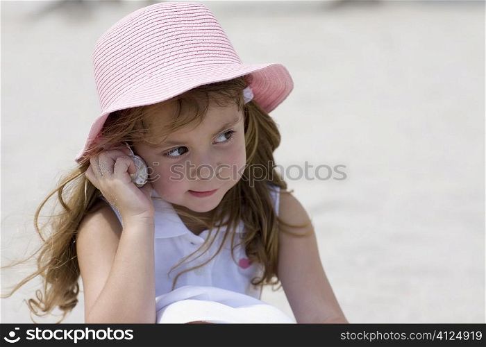 Close-up of a girl listening to a conch shell